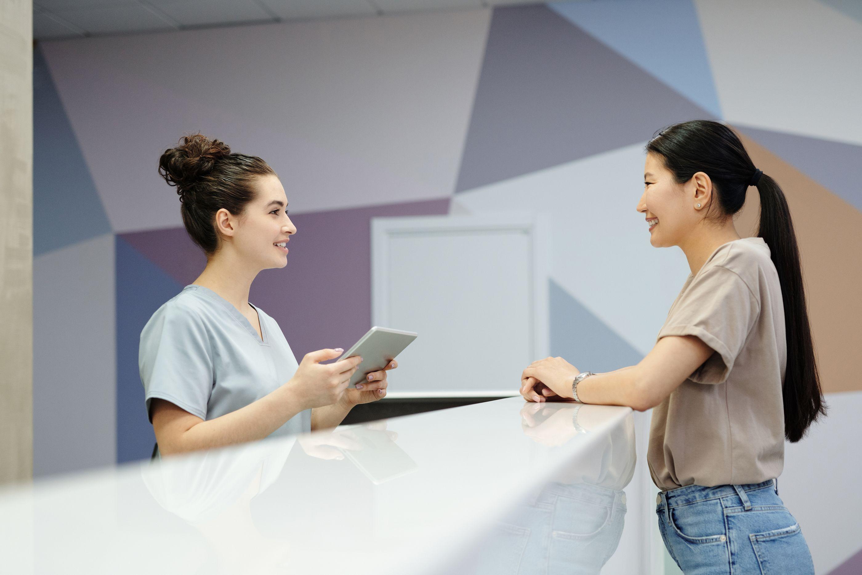 Wellness receptionist and member consulting at a modern front desk counter